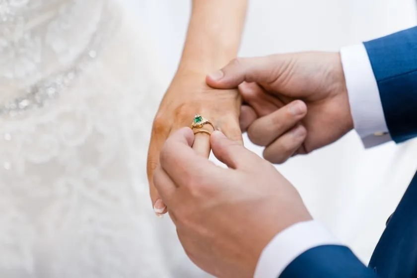 Ein Brautpaar steckt beim heiraten während der Hochzeit in der Hochzeitslocation Palais Coburg Ihr Ringe an